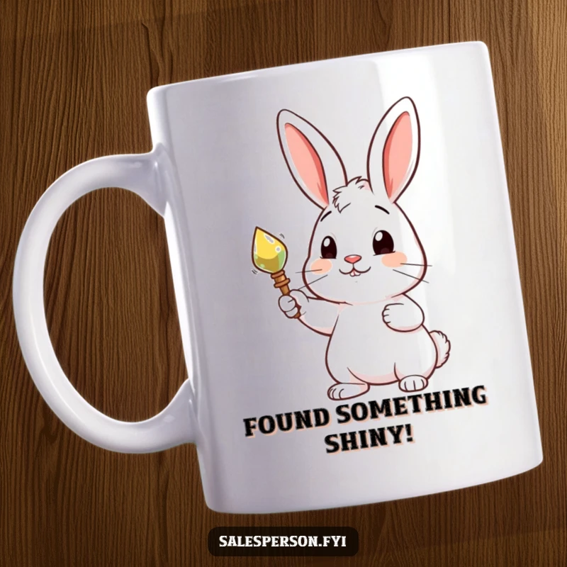 Funny mug featuring a curious rabbit proudly presenting a shiny, desirable object, showcasing possessiveness and delight.