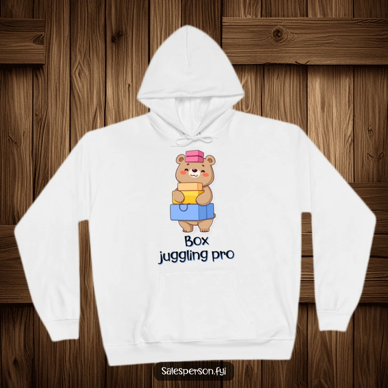 Funny hoodie featuring a confident bear with a grin, perfectly balancing a stack of brightly colored boxes, offering cozy strength.